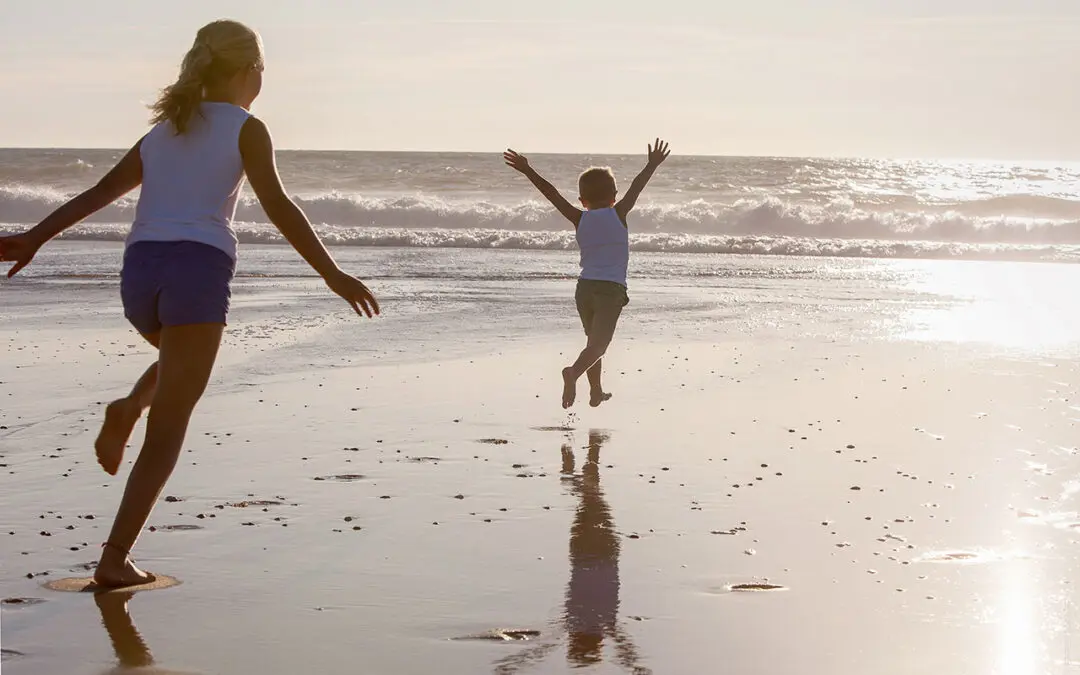 Twee kinderen rennen richting de zee op een strand van de Atlantische Kust in Frankrijk.