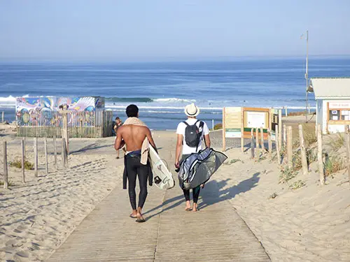 Twee surfers lopen richting het strand van Le Porge in Frankrijk.