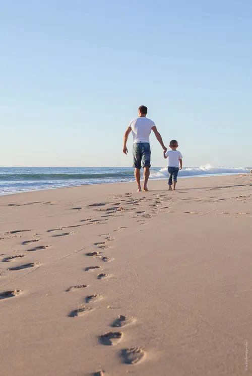 Een man en een jongen laten voetstappen achter in het strand aan de Atlantische Kust van Frankrijk.