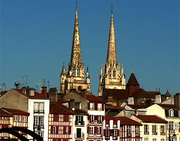 Een straat in Bayonne met twee torens op de achtergrond.