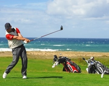 Een man is aan het golfen met de zee op de achtergrond in Moliets.