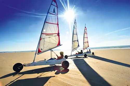 Drie mensen blowkarten op het strand van de Atlantische Kust in Frankrijk.