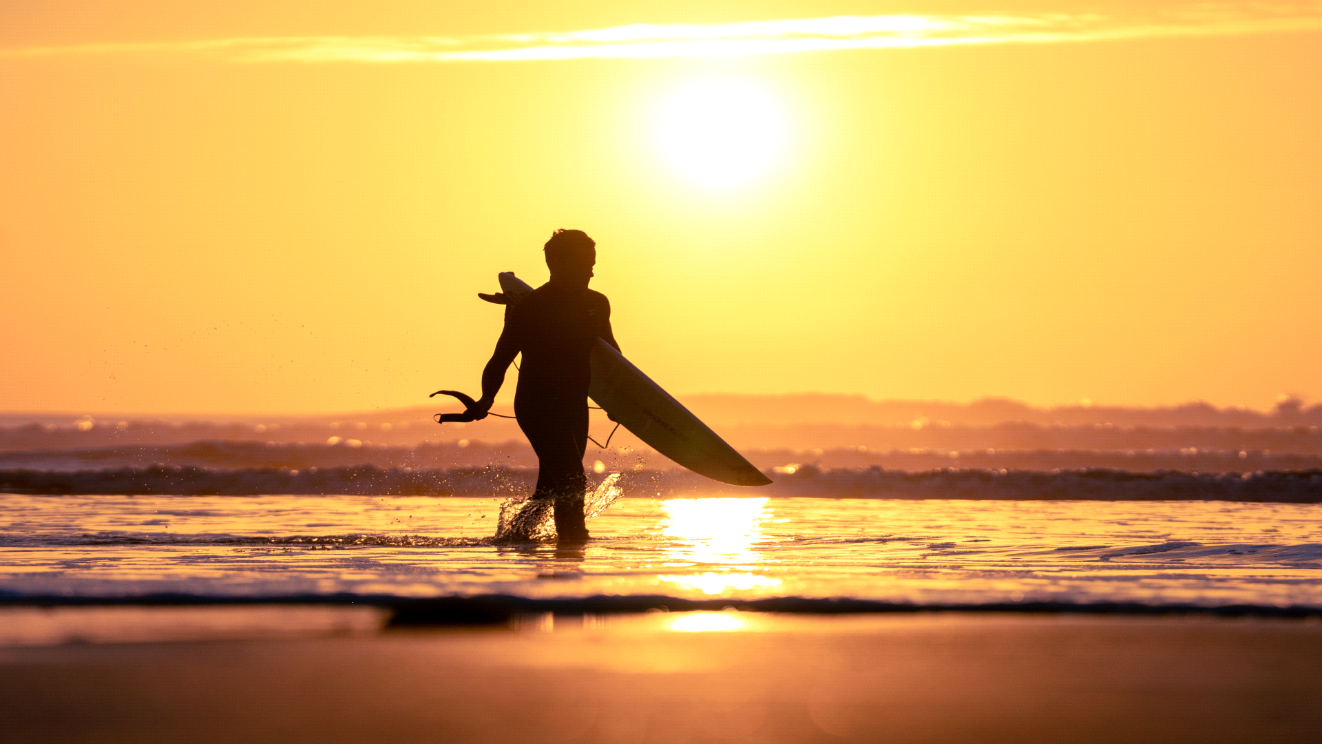 Een surfer loopt de zee in bij zonsondergang op het Ile d'Oleron.